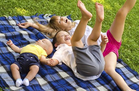 Two brothers and sister having fun on the meadow on sunny summer day.