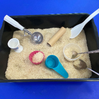 Kitty Litter tray filled with rice and scoops to make a sensory bin play activity